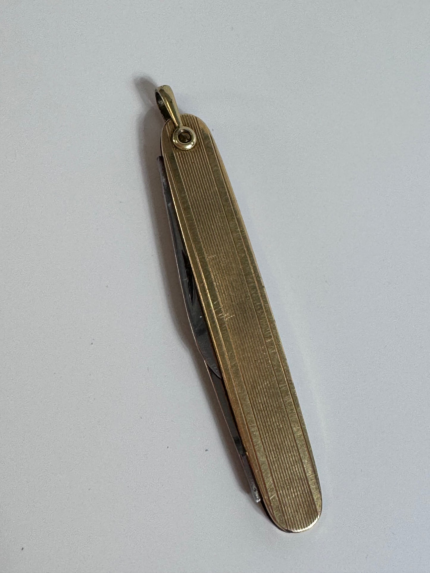 Vintage 10K gold pocket knife pendant with working steel blade, engine turned texture and engraved details, functional jewelry
