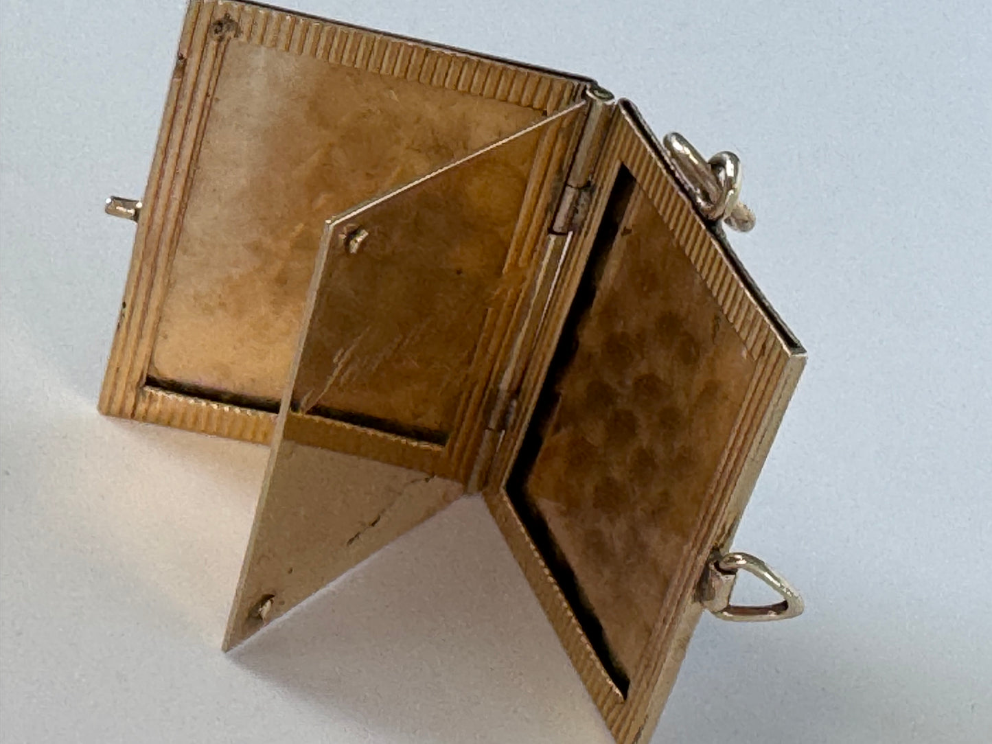 Vintage 14K gold book locket with hinged pages, engine-turned texture, engraved details, multiple photo compartments