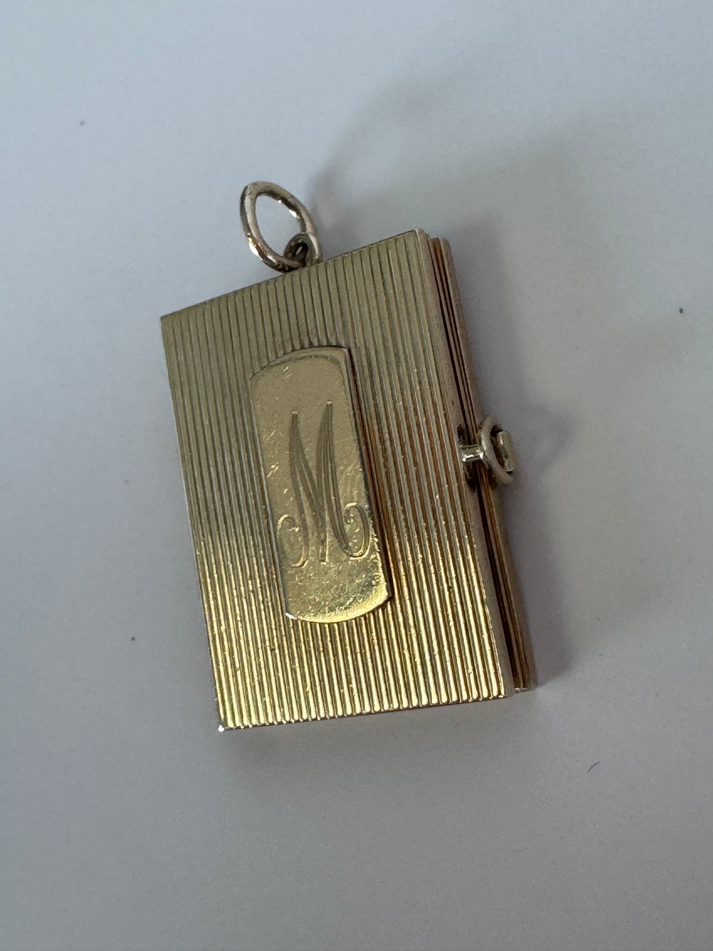 Vintage 14K gold book locket with hinged pages, engine-turned texture, engraved details, multiple photo compartments