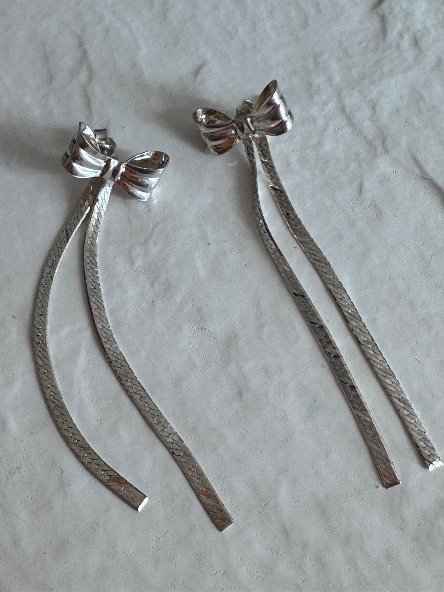 Estate 1980s sterling silver bow drop earrings with textured dangles measuring approximately 2.5 inches long showing dramatic vintage design