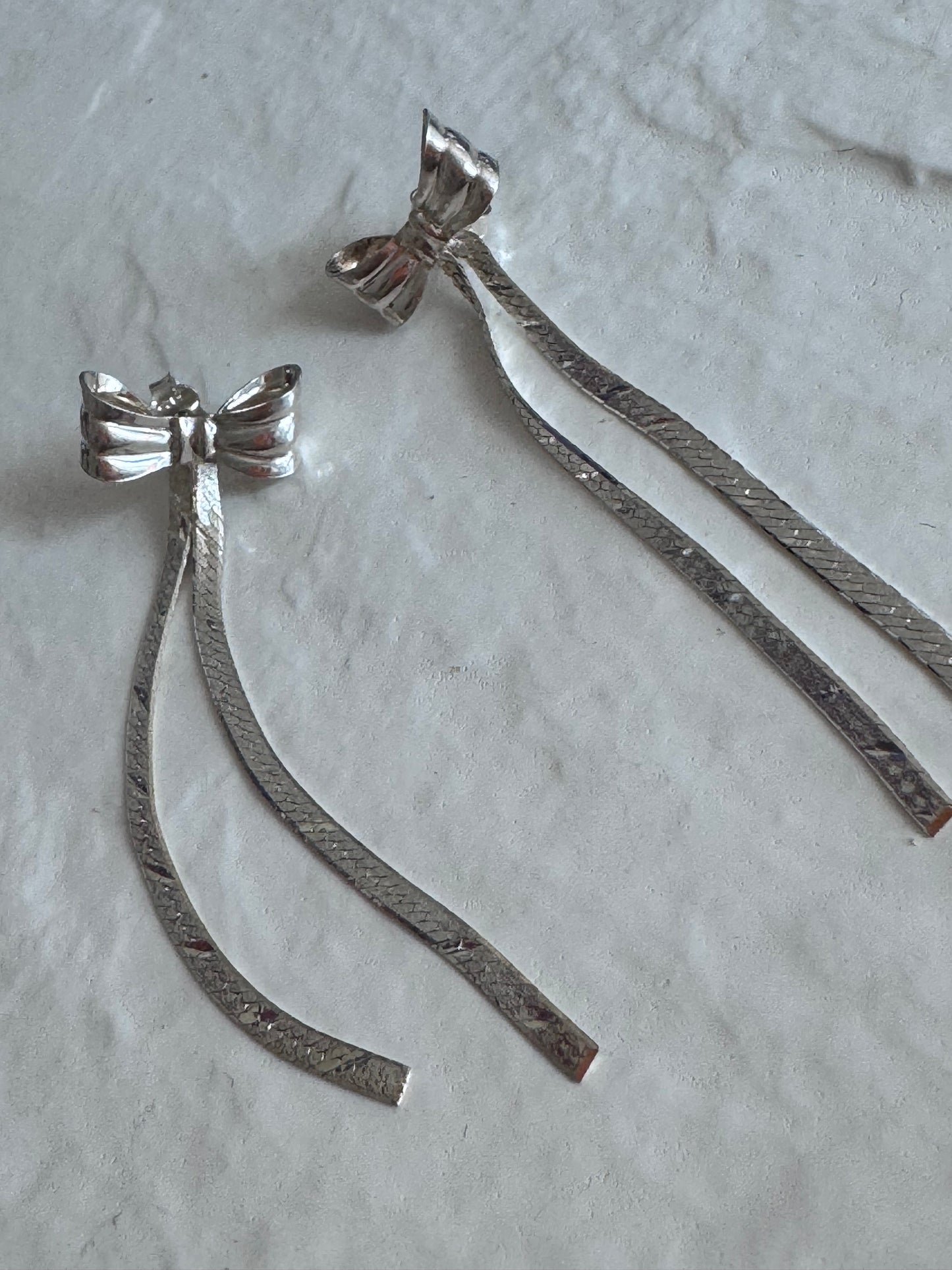 Estate 1980s sterling silver bow drop earrings with textured dangles measuring approximately 2.5 inches long showing dramatic vintage design