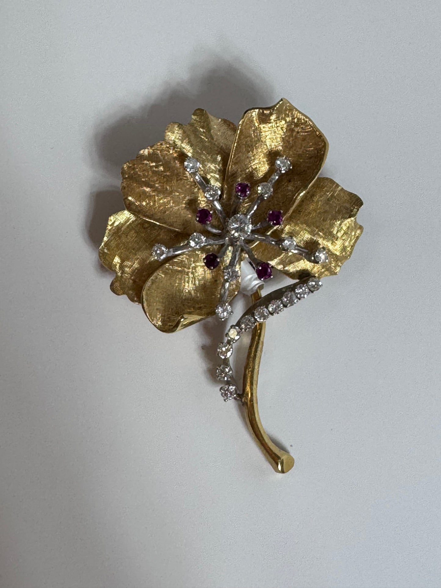 Gold brooch with gemstones on a light gray background