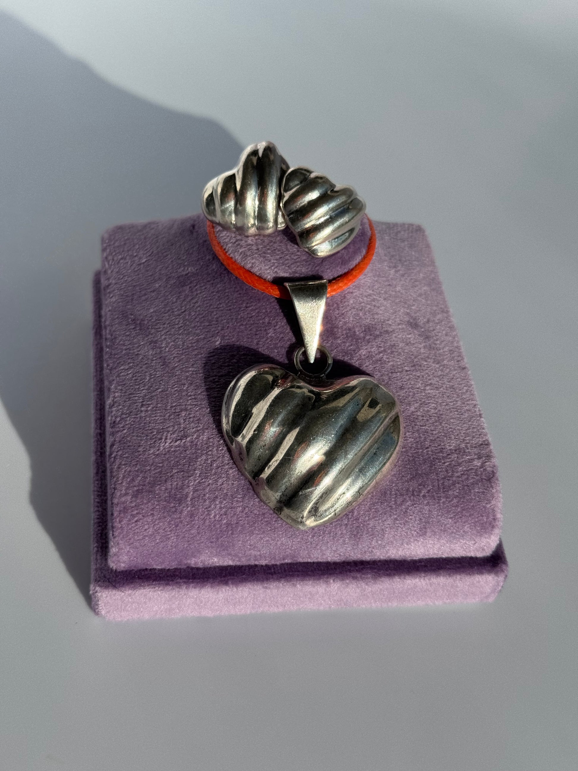 Sterling silver puffy heart jewelry set including cuff bracelet, stud earrings, and pendant with orange cord