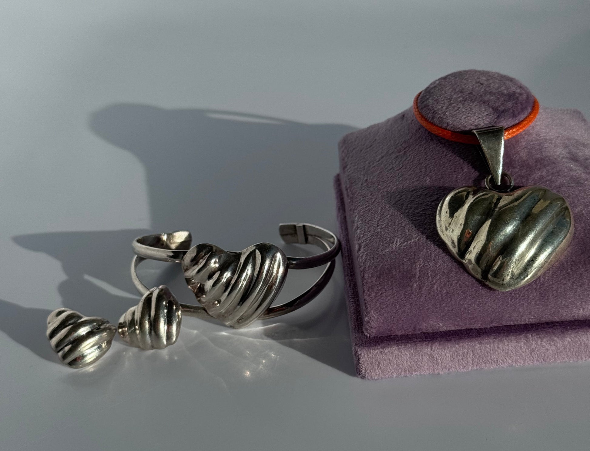 Sterling silver puffy heart jewelry set including cuff bracelet, stud earrings, and pendant with orange cord