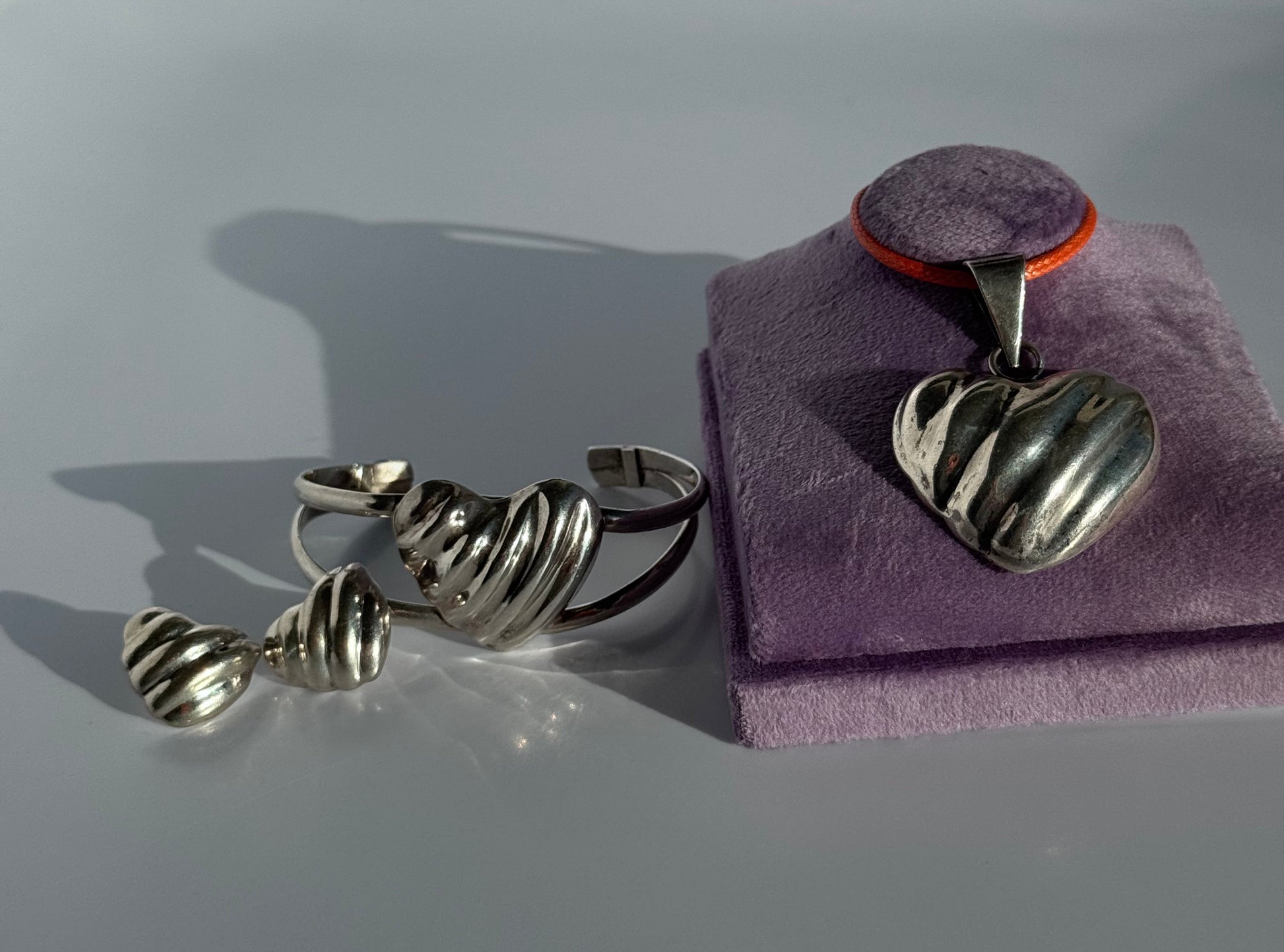 Sterling silver puffy heart jewelry set including cuff bracelet, stud earrings, and pendant with orange cord