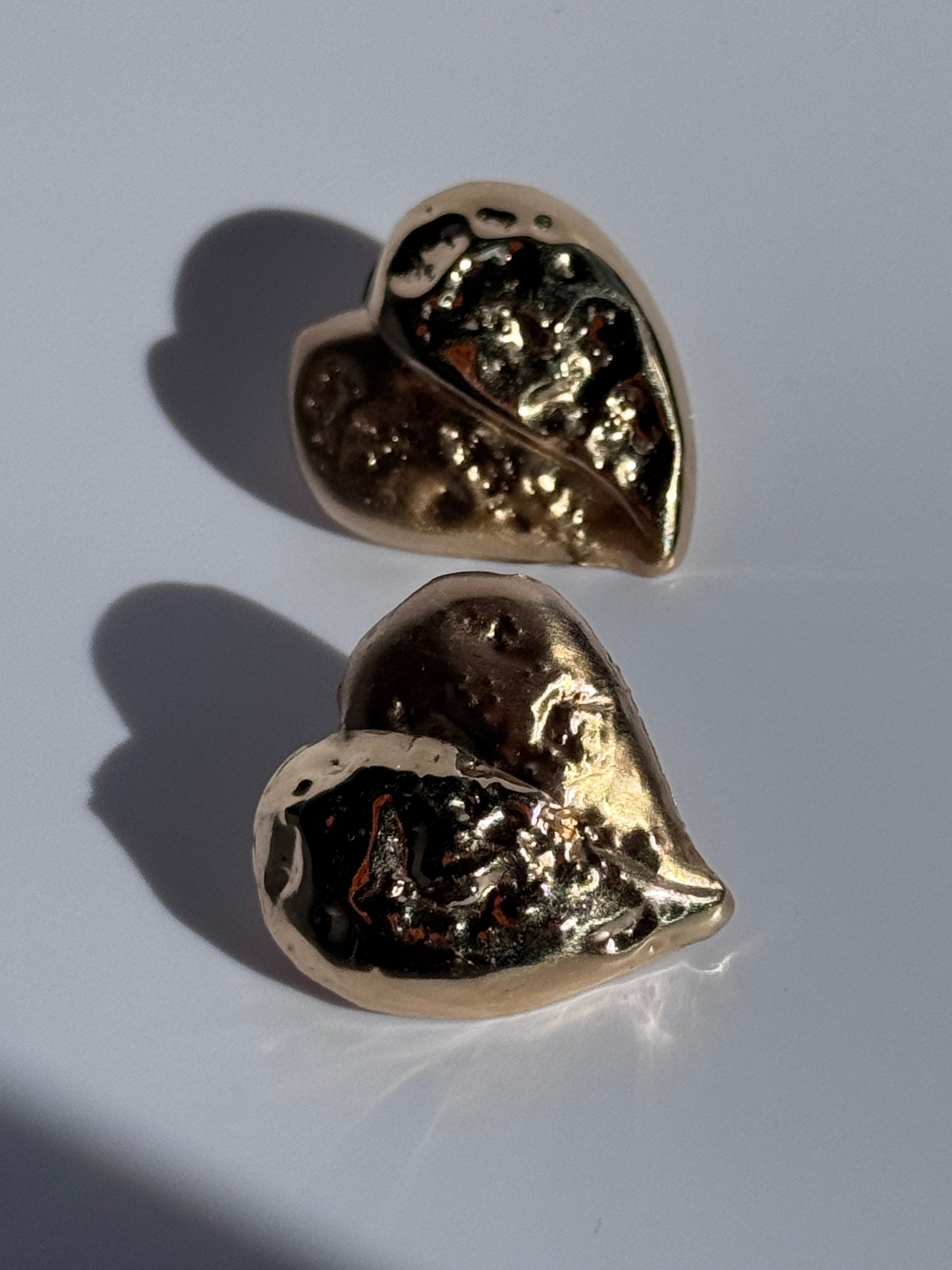 Estate vintage 14K yellow gold puffy heart stud earrings with textured repousse work showing shiny and matte contrast finishes