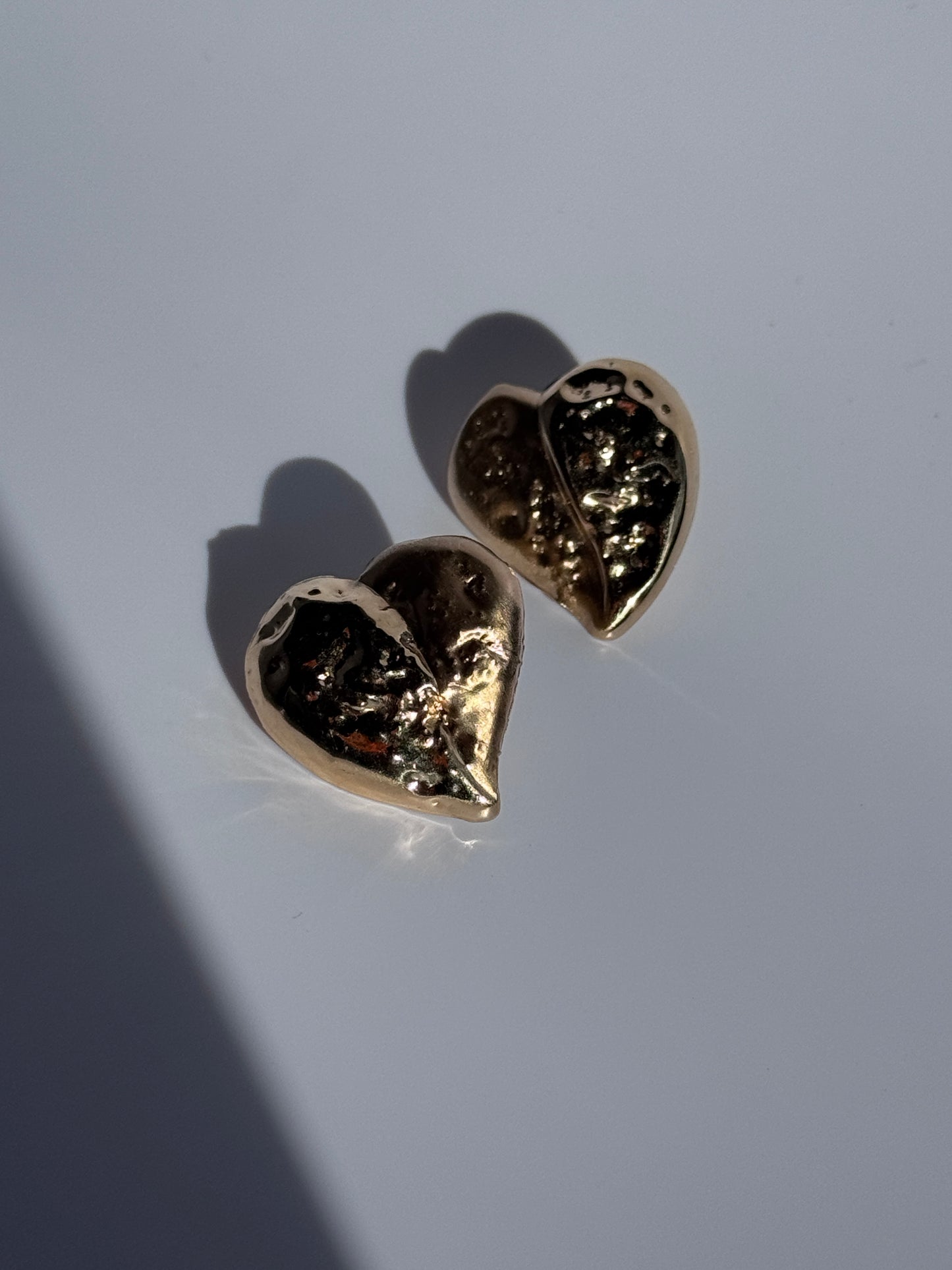 Estate vintage 14K yellow gold puffy heart stud earrings with textured repousse work showing shiny and matte contrast finishes