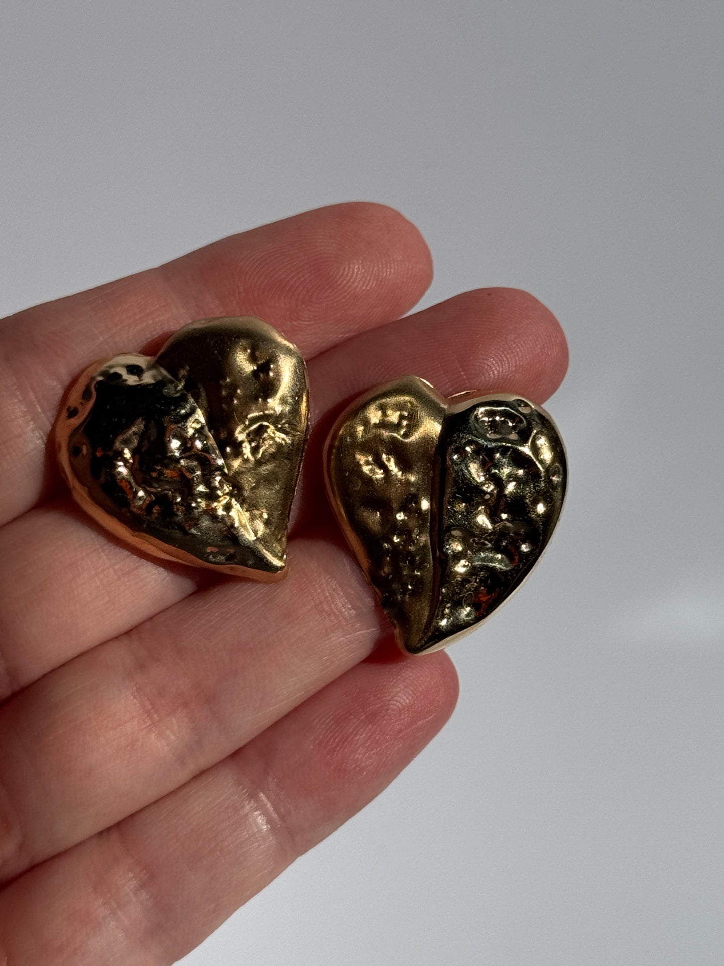 Estate vintage 14K yellow gold puffy heart stud earrings with textured repousse work showing shiny and matte contrast finishes