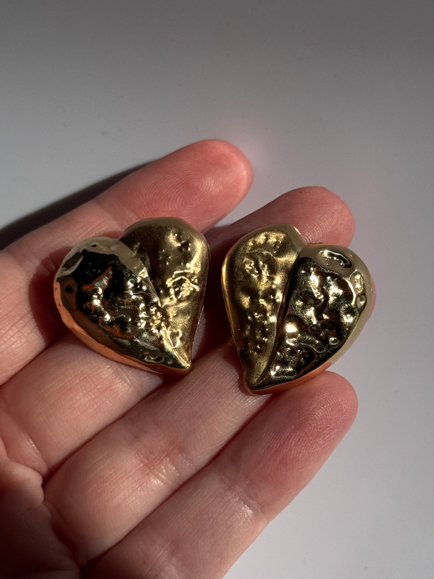 Estate vintage 14K yellow gold puffy heart stud earrings with textured repousse work showing shiny and matte contrast finishes