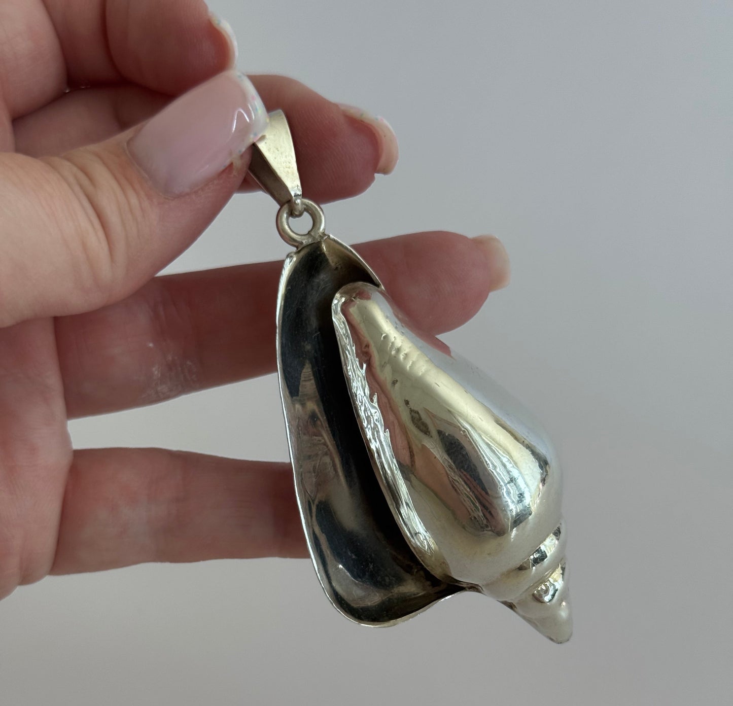Large vintage sterling silver conch shell pendant with high-polish finish, showing detailed spiral shell design and secure bail