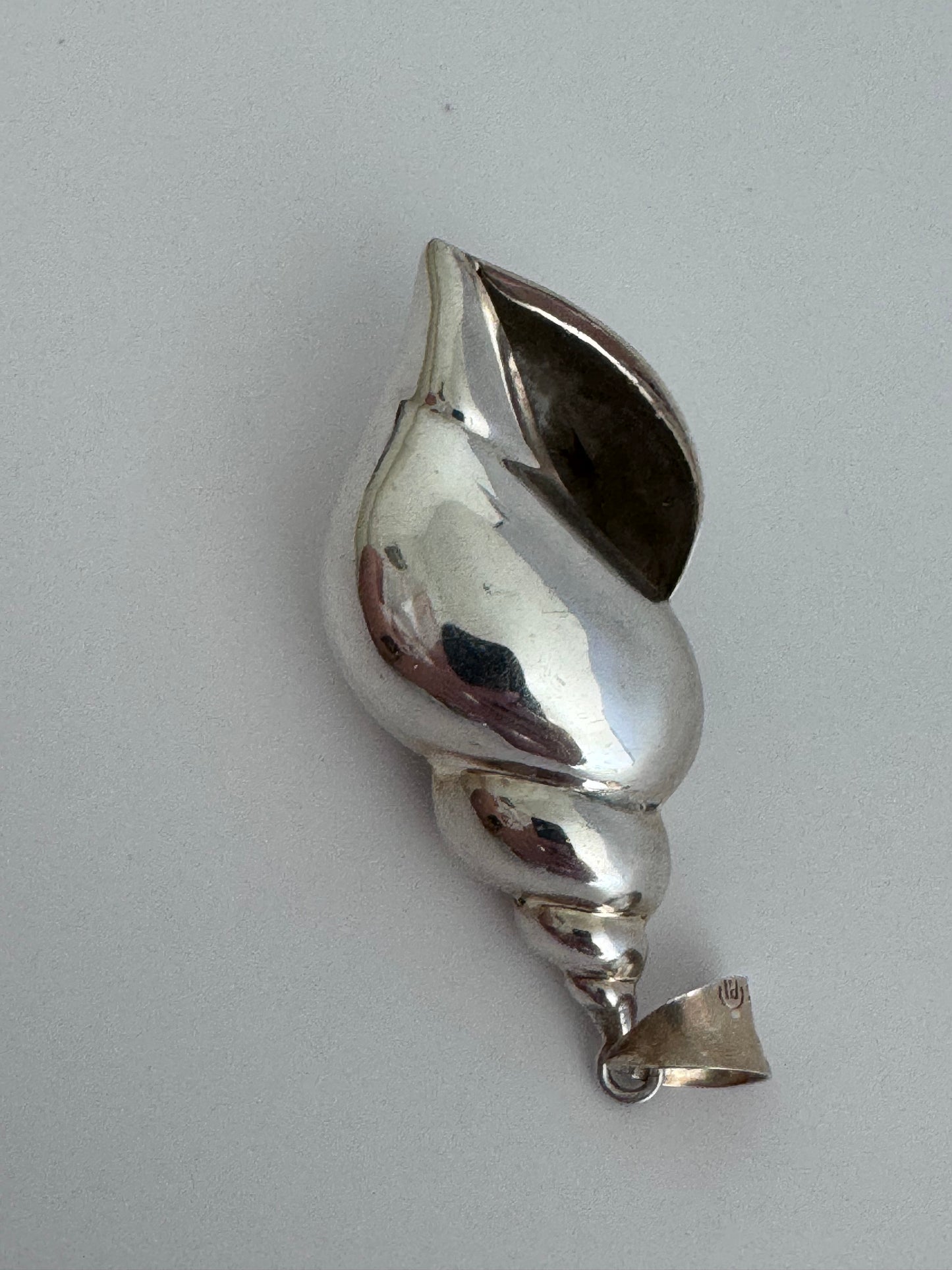 Large vintage sterling silver conch shell pendant with AI signature, showing detailed spiral shell design and high-polish finish