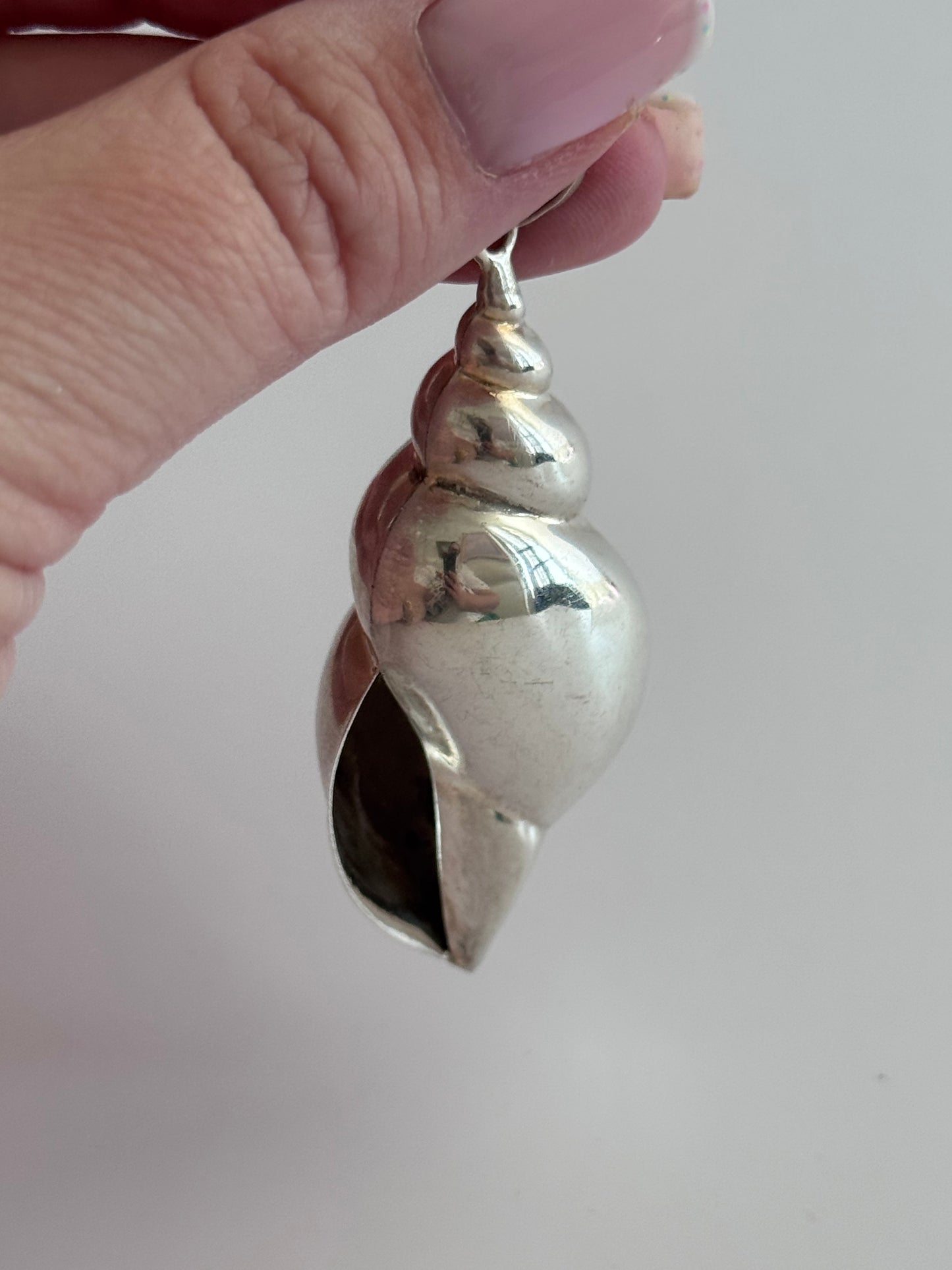 Large vintage sterling silver conch shell pendant with AI signature, showing detailed spiral shell design and high-polish finish