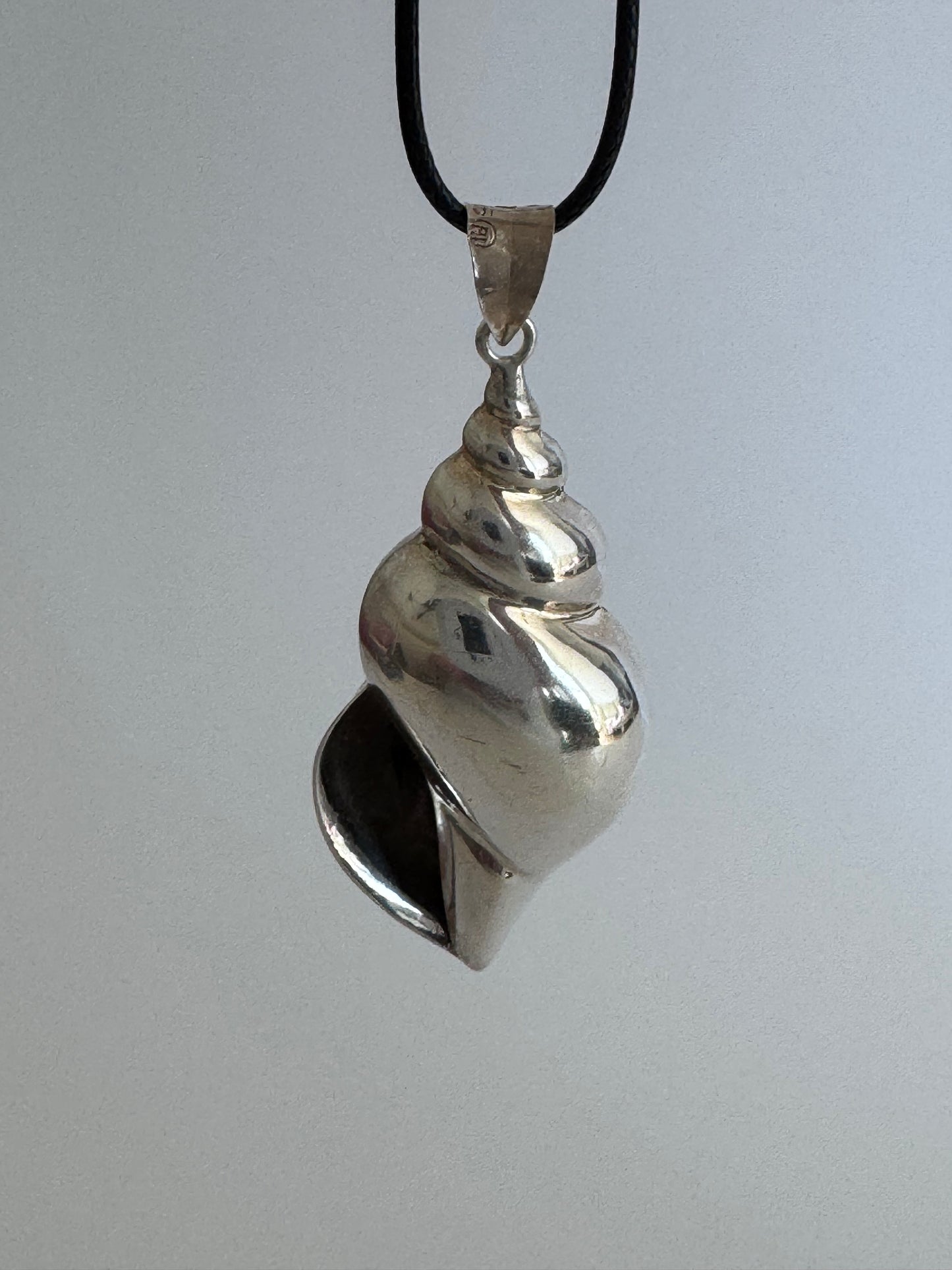 Large vintage sterling silver conch shell pendant with AI signature, showing detailed spiral shell design and high-polish finish