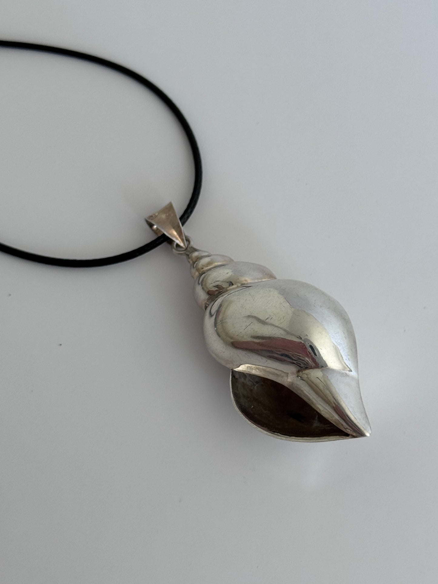 Large vintage sterling silver conch shell pendant with AI signature, showing detailed spiral shell design and high-polish finish