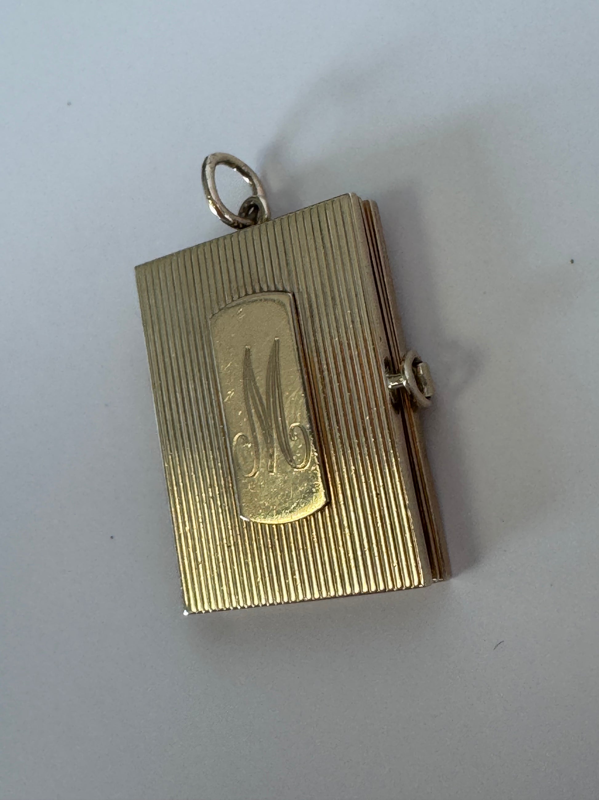 Vintage 14K gold book locket with hinged pages, engine-turned texture, engraved details, multiple photo compartments