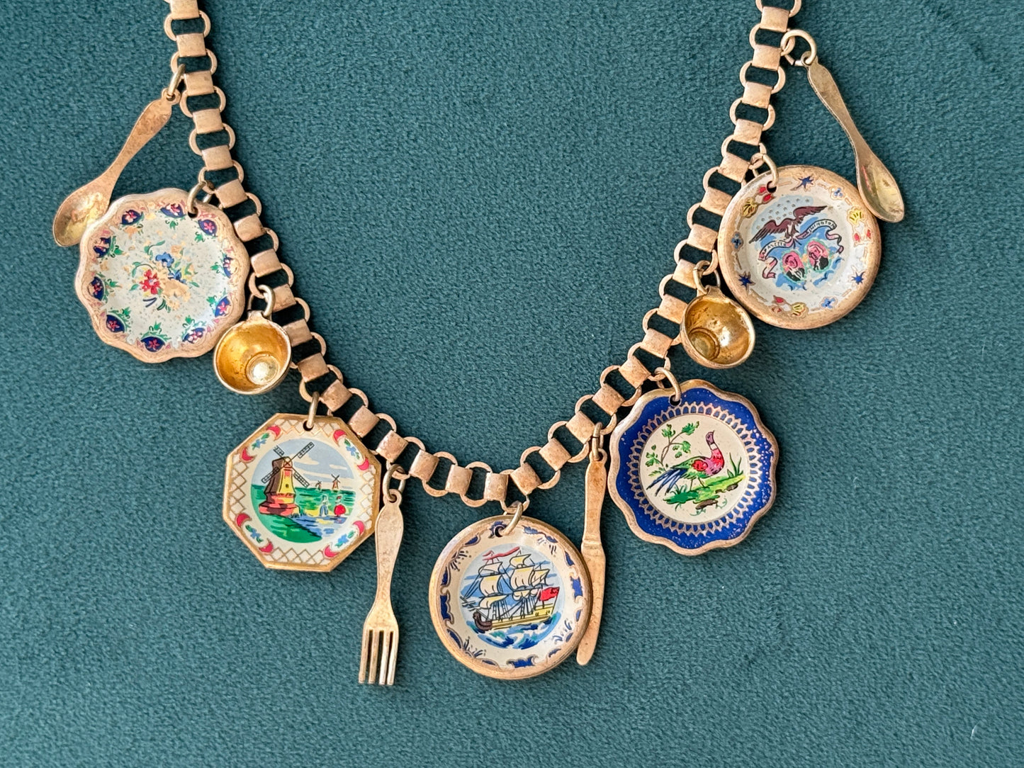Decorative necklace with small dishes and spoons on a teal background