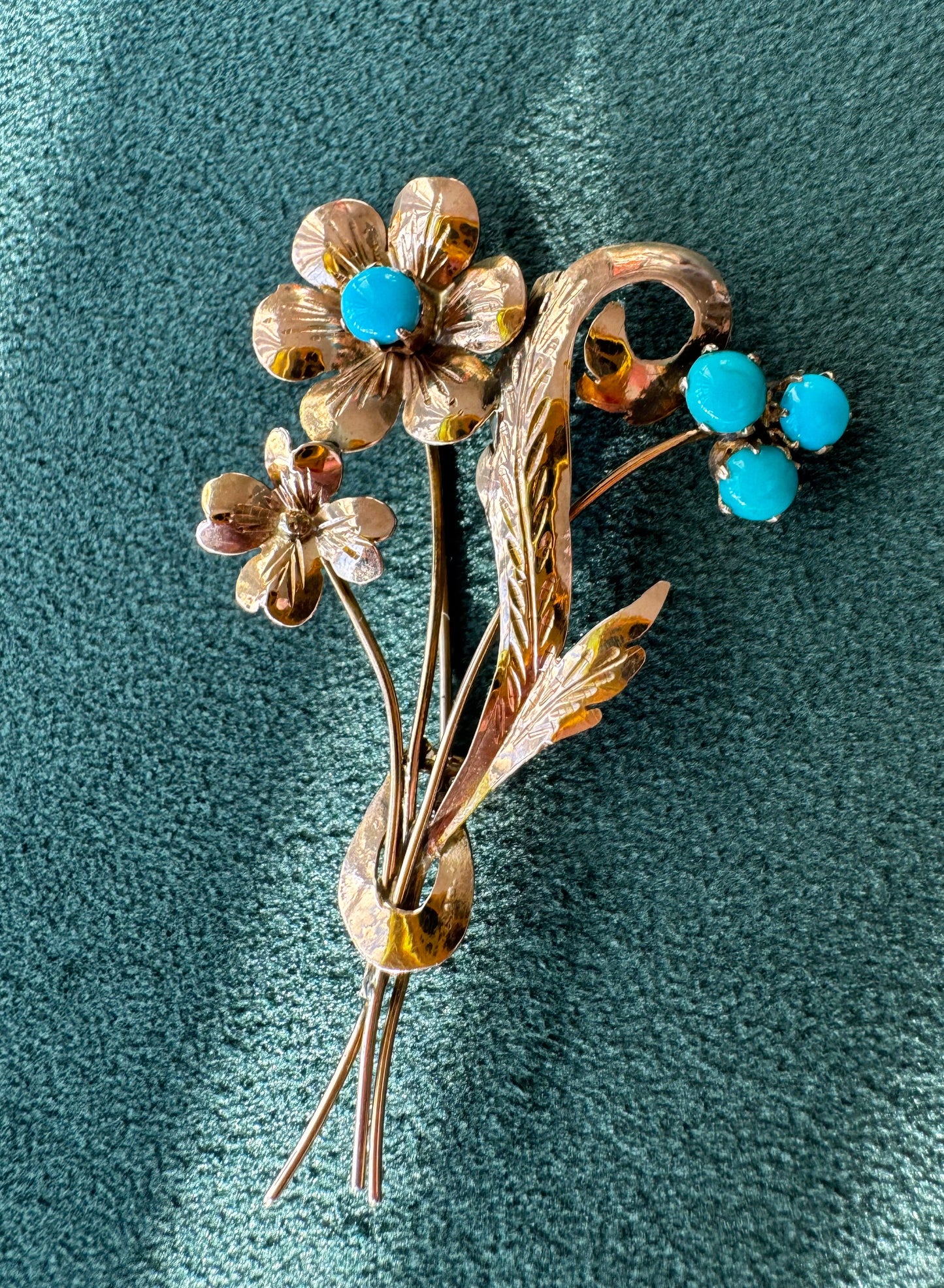 Floral brooch with turquoise stones on a textured teal background