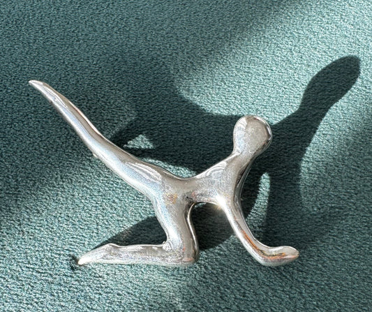Silver abstract sculpture on a textured green surface