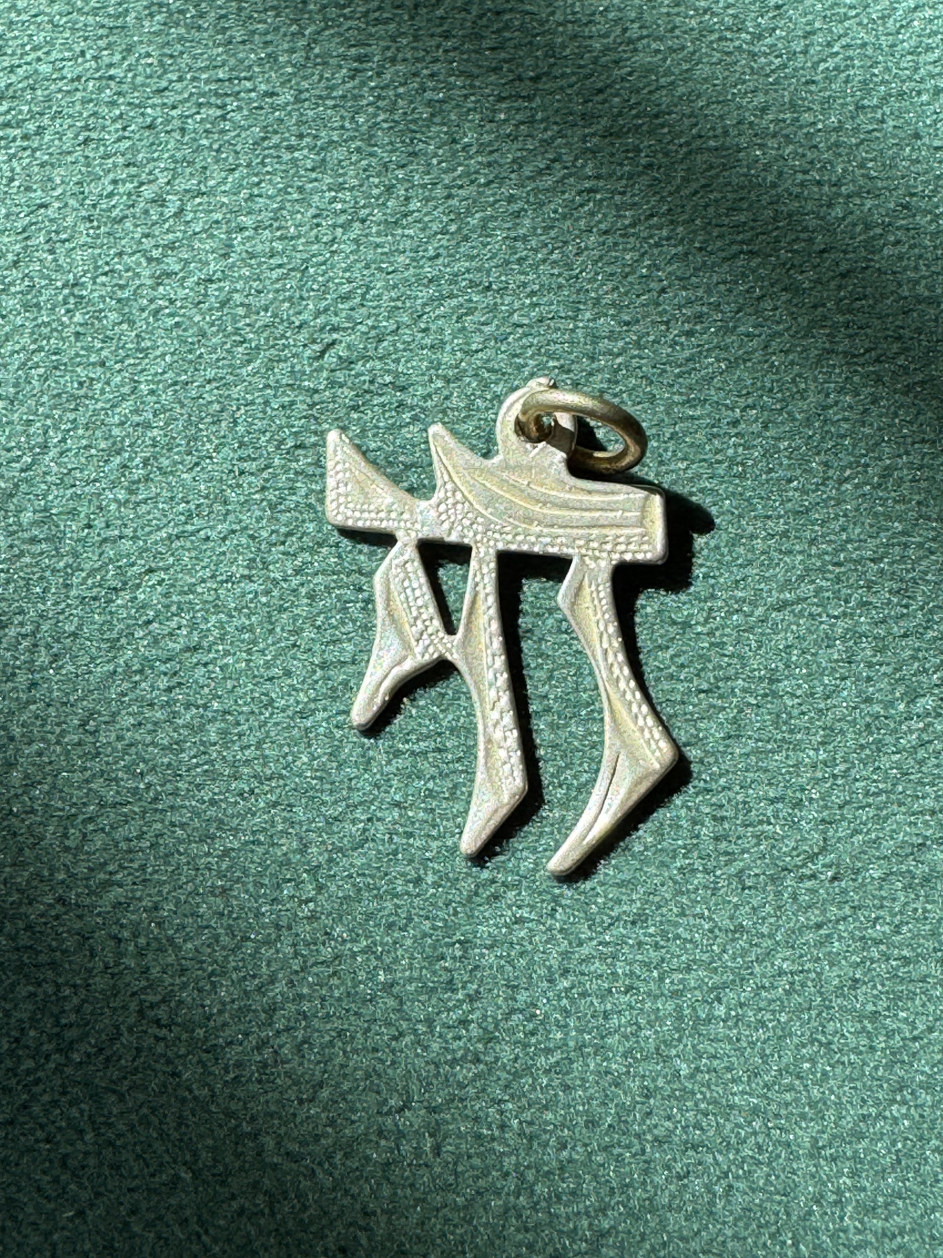 Silver pendant on a green textured background