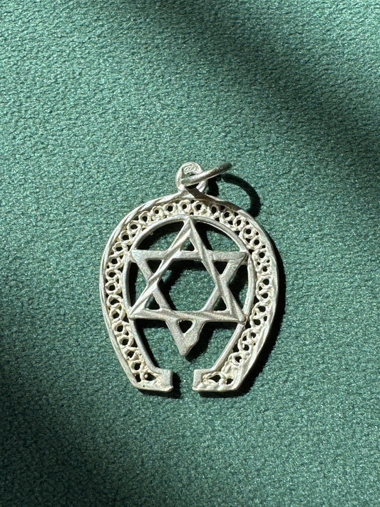 Silver pendant with Star of David and horseshoe design on a green background
