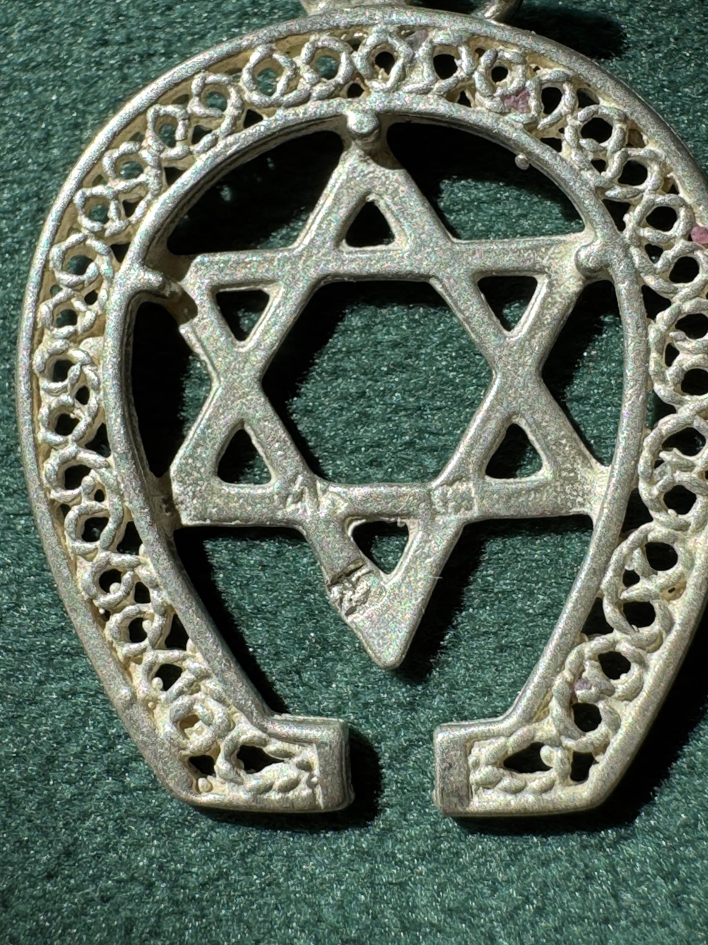 Decorative silver horseshoe with Star of David on a green background