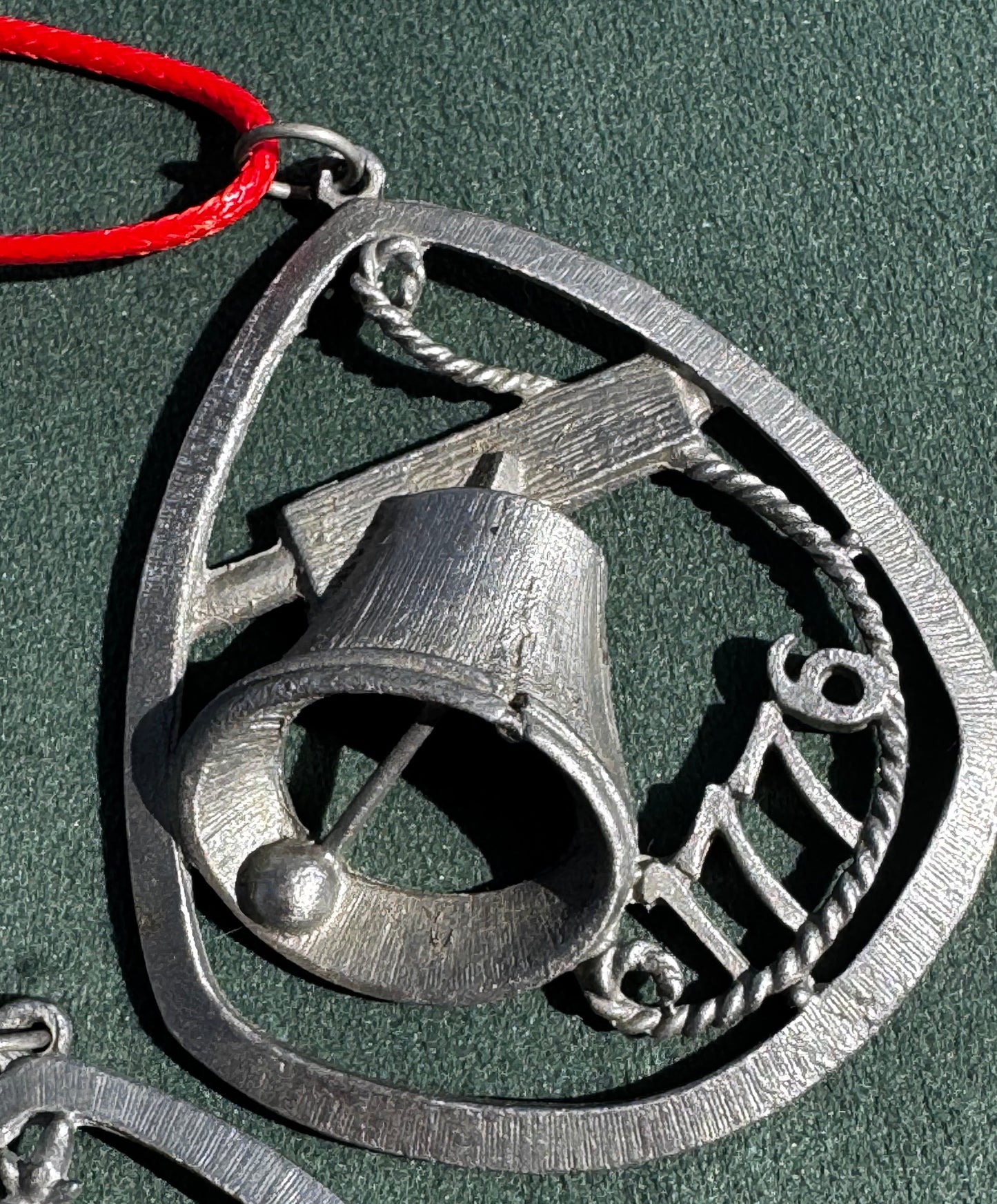 Metallic bell with 'ZUZ' engraving on a green background
