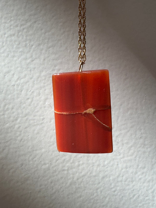 Estate 14K gold pendant featuring natural red carnelian rectangle with dramatic gold strike mineral inclusions embodying wabi sabi aesthetics