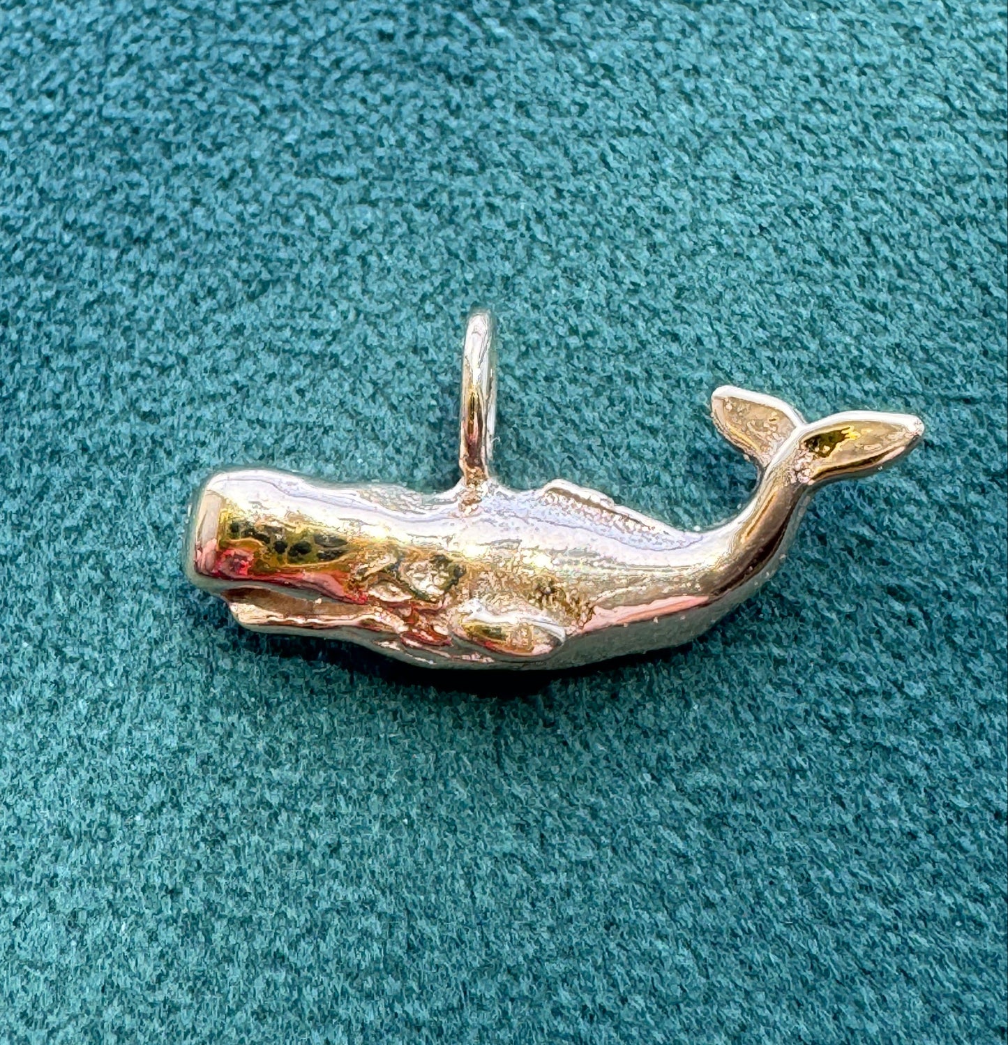 gold whale pendant on a textured blue background