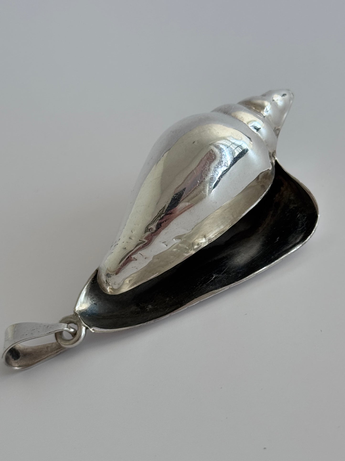 Large vintage sterling silver conch shell pendant with high-polish finish, showing detailed spiral shell design and secure bail