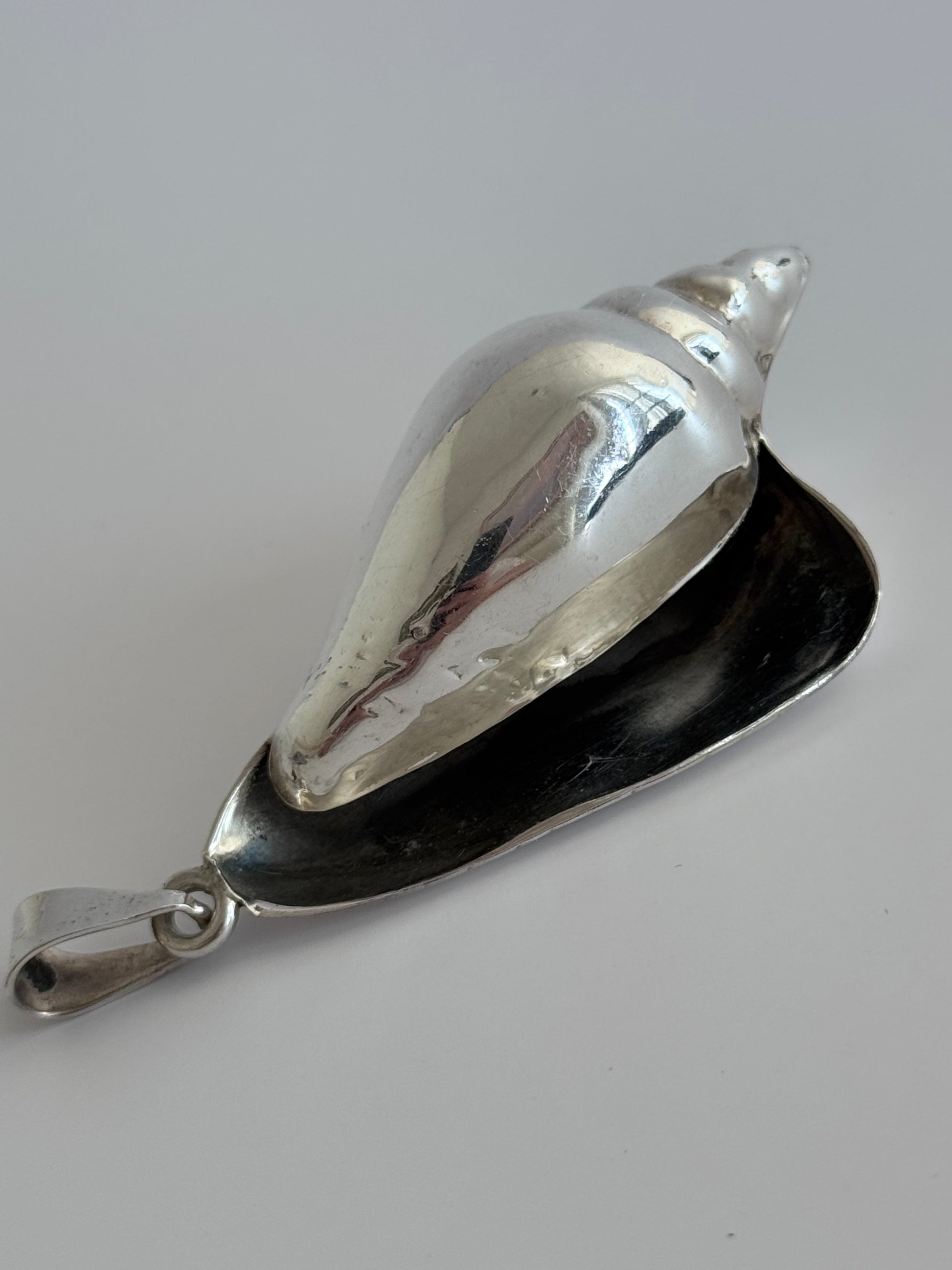 Large vintage sterling silver conch shell pendant with high-polish finish, showing detailed spiral shell design and secure bail