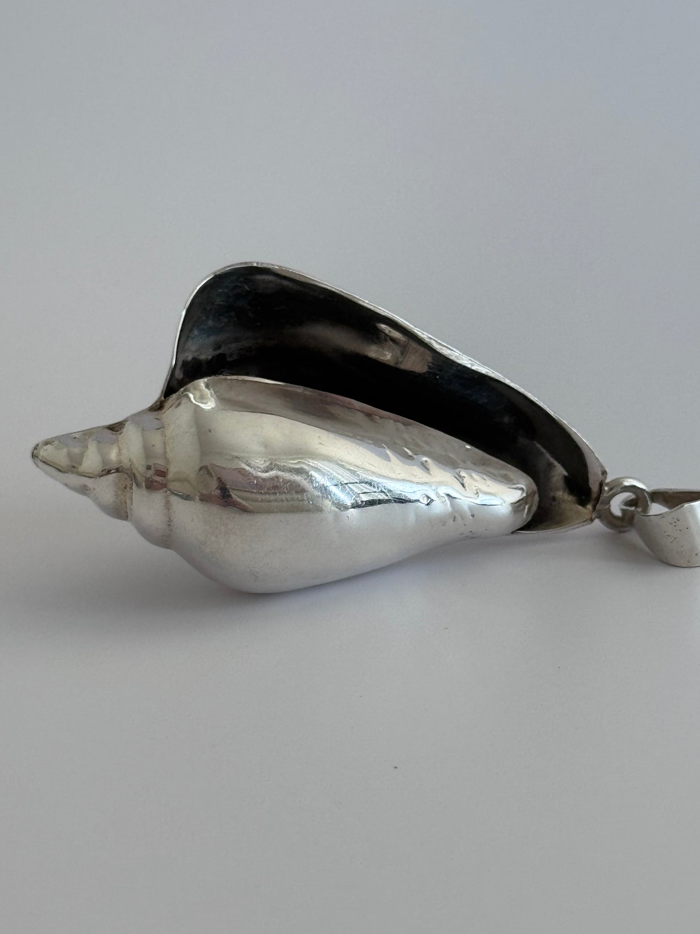 Large vintage sterling silver conch shell pendant with high-polish finish, showing detailed spiral shell design and secure bail