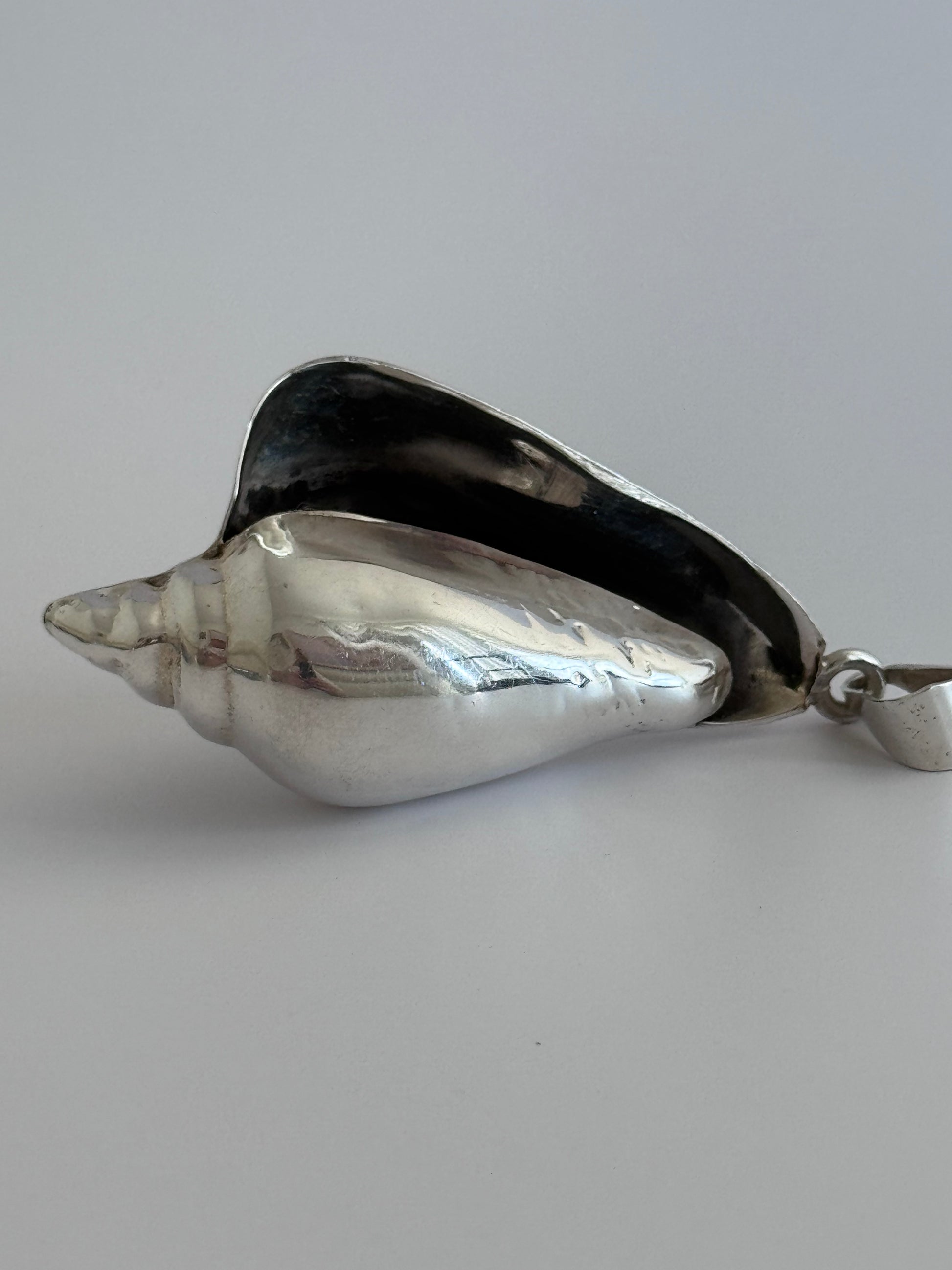 Large vintage sterling silver conch shell pendant with high-polish finish, showing detailed spiral shell design and secure bail