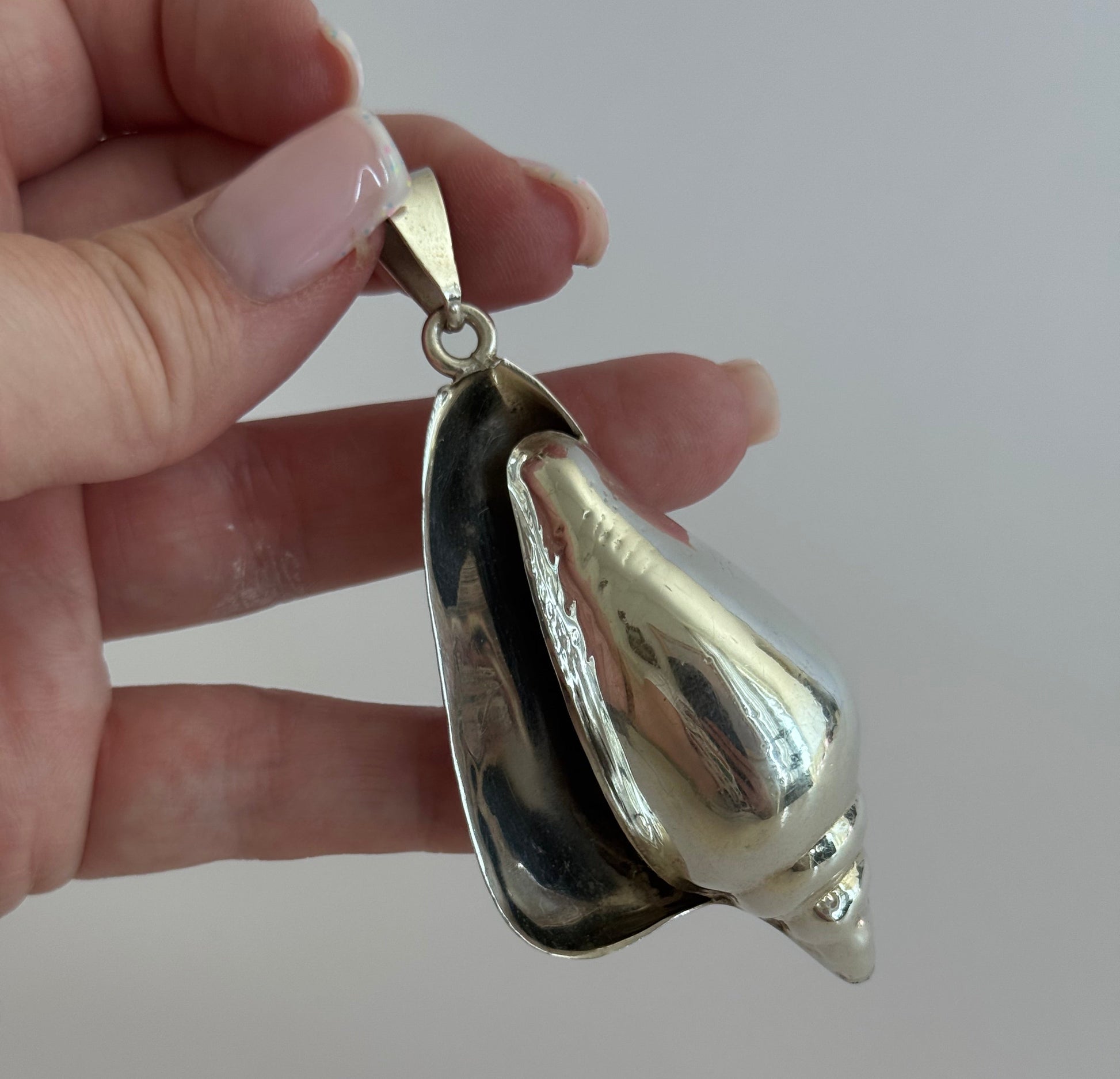 Large vintage sterling silver conch shell pendant with high-polish finish, showing detailed spiral shell design and secure bail