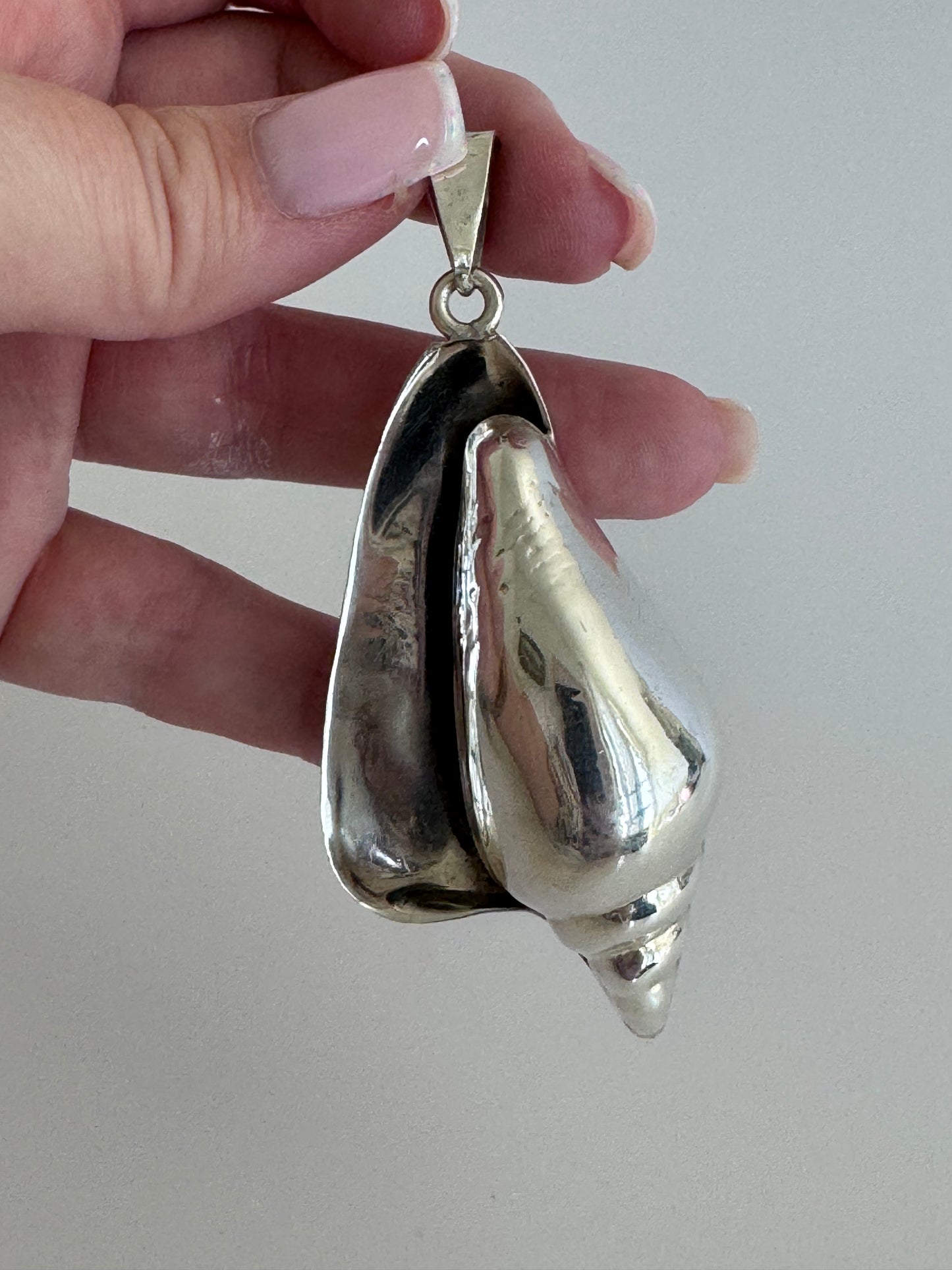 Large vintage sterling silver conch shell pendant with high-polish finish, showing detailed spiral shell design and secure bail